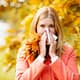 Girl with cold rhinitis on autumn background. Fall flu season. Ill sick sneezing woman. Handkerchief, vaccine against influenza virus Caught Cold Headache Allergy runny nose